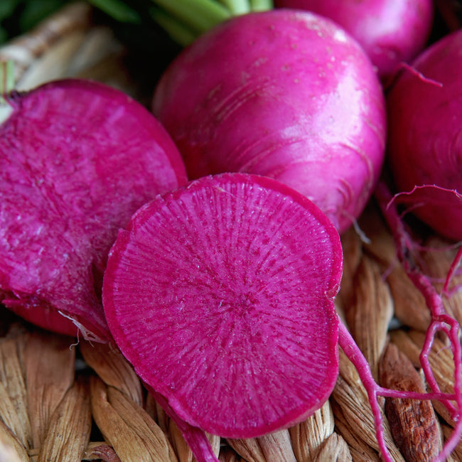 Close-up of wonderland radishes with a sliced radish on a woven surface