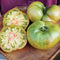 Close-up of Ananas Noire tomato showing multicolored skin and bright green flesh with red streaks on a wooden board