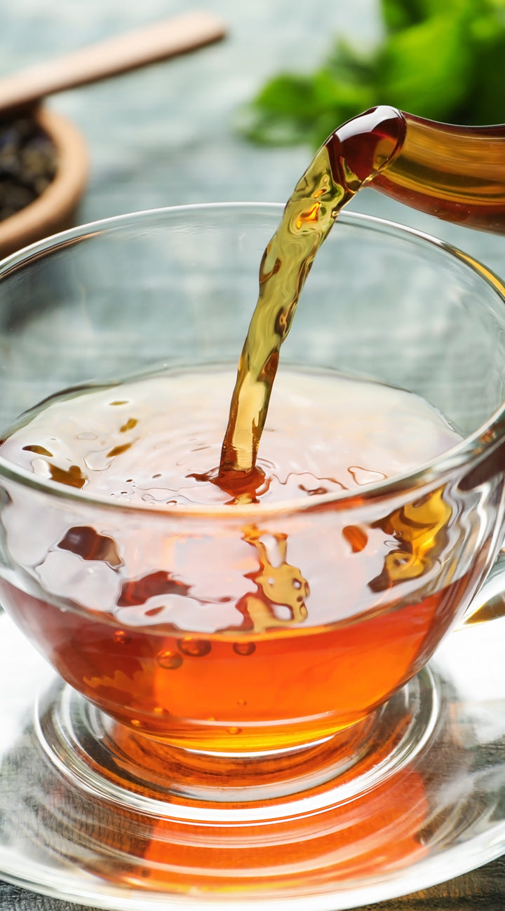yerba buena Tea being poured into a glass cup with a blurred background