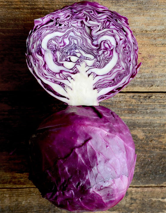Purple cabbage cut in half on a wooden surface