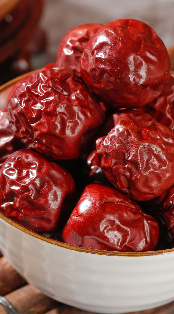 Close-up of a bowl filled with jujubes on a wooden surface.