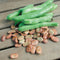 Close-up of Broad Windsor fava bean seeds and green pods showing buff-colored seeds on a wooden surface