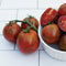 Purple Zebra tomatoes with green stems on a white tiled surface
